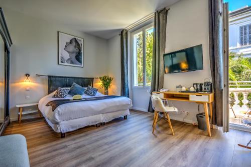 1 dormitorio con 1 cama y escritorio con ordenador en Villa Claudia Hotel Cannes Centre - Parking, en Cannes