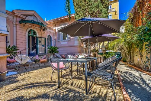 a table and chairs with an umbrella in front of a house at Villa Claudia Hotel Cannes Centre - Parking in Cannes