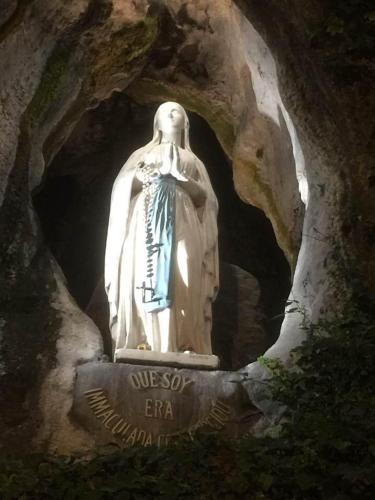 a statue of a woman sitting in a cave at La Sainte Famille in Lourdes