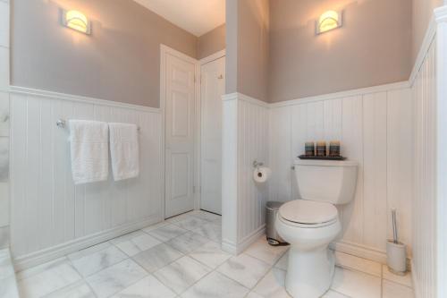 a white bathroom with a toilet and towels at Downtown Luxury Victorian Retreat in Toronto