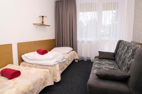 a hotel room with two beds and a couch at Ośrodek Wypoczynkowy Ania Dźwirzyno in Dźwirzyno