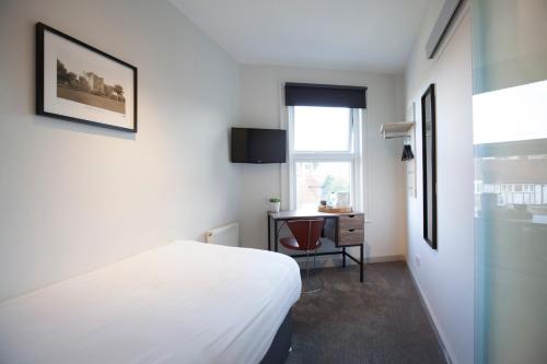 a bedroom with a bed and a desk and a window at Asperion Hotel in Guildford