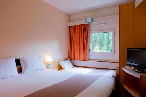 um quarto de hotel com duas camas e uma janela em ibis Grenoble Université em Gières