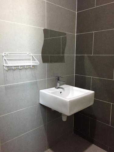 a bathroom with a white sink in a tiled wall at Homestay DTepian Bayu Bandar Seri Impian Kluang in Kluang
