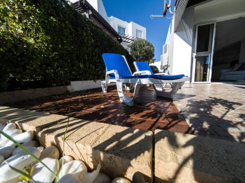 two chairs sitting on a patio next to a wall at Blue Bay Beach House in Larnaka