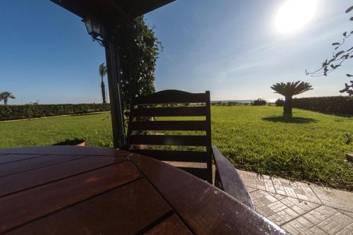 a wooden table and a chair sitting next to a field at Blue Bay Beach House in Larnaka