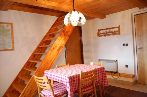 a dining room with a table and a wooden staircase at Chata Eliška in Příkrý
