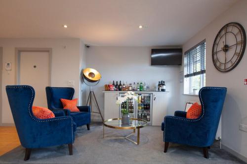 a living room with blue chairs and a table and a clock at Asperion Hotel in Guildford