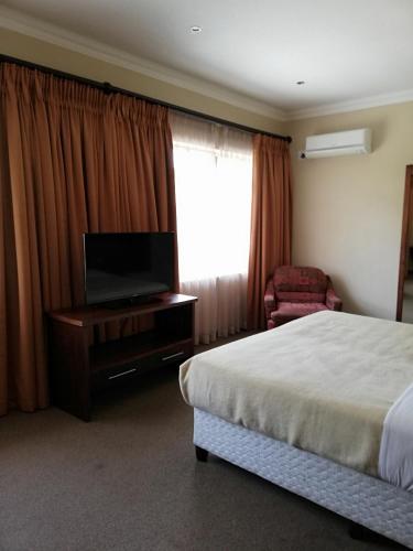 a bedroom with a bed and a flat screen tv at The Shakespeare Inn in Vanderbijlpark