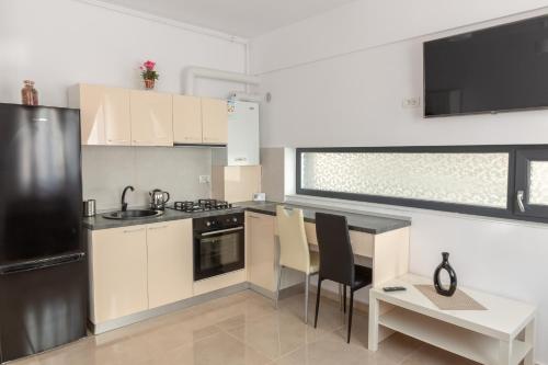a kitchen with white cabinets and a table with chairs at Studio Ambiance , Mamaia in Mamaia Nord