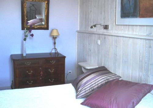 a bedroom with a bed and a dresser and a mirror at Maison d'hôtes La Tuilerie in Peschadoires
