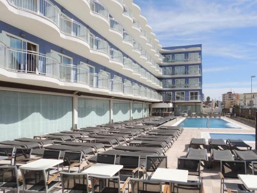 an outdoor patio with tables and chairs next to a building at Hotel Cesar Augustus in Cambrils