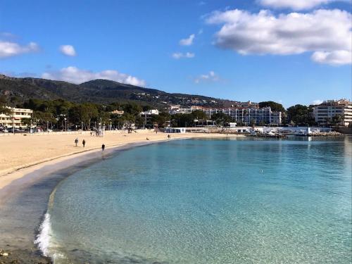 a beach with people walking on the sand and water at Apartamentos Las Palmeras in Palmanova