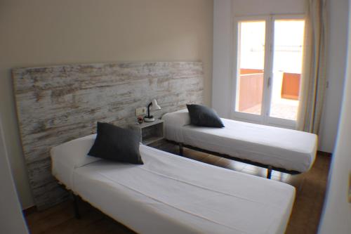 dwa łóżka w pokoju z oknem w obiekcie Agi Sant Jordi w mieście Roses