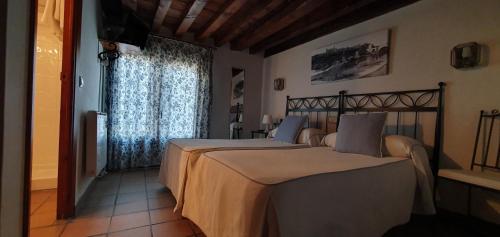 1 dormitorio con 2 camas y ventana en Hostal la posada de Zocodover, en Toledo