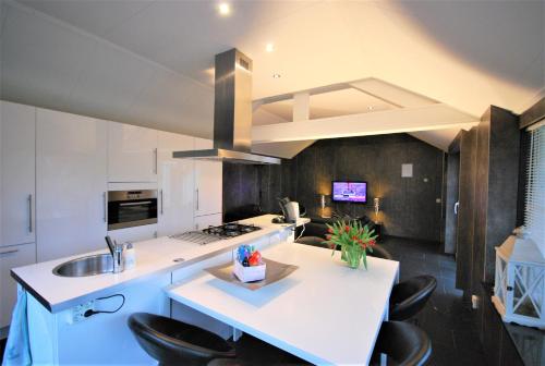 uma cozinha com um lavatório e um balcão com cadeiras em Comfortabele Vrijstaande Bungalow 3 em Stramproy