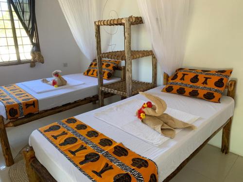 two beds in a room with orange and black at More Africa Guesthouse in Paje