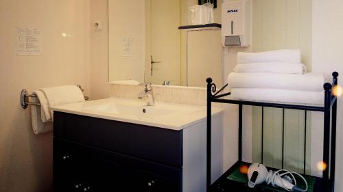 a bathroom with a sink and a mirror and towels at Hôtel Fontaine Morlaix in Morlaix