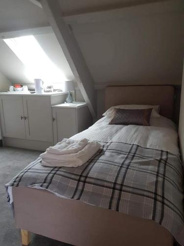 a bedroom with a bed with a plaid blanket at The Swan in Topcliffe