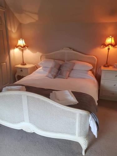 a white bed in a bedroom with two lamps at The Swan in Topcliffe