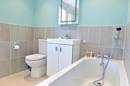 a bathroom with a toilet and a tub and a sink at St Mary's Cottage in Eastbourne