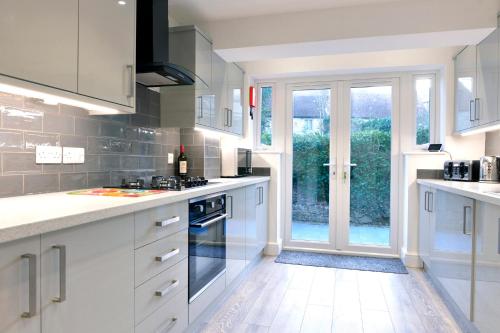 a kitchen with white cabinets and a large window at St Mary's Cottage in Eastbourne