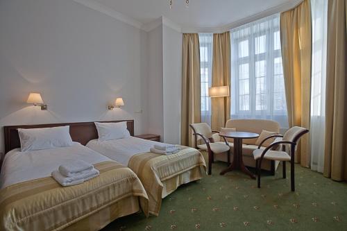 ギジツコにあるHotel Masoviaのベッド、テーブル、椅子が備わるホテルルームです。