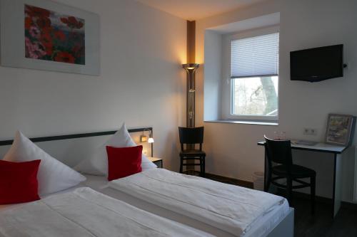 a bedroom with a bed with red pillows and a desk at Hotel zwischen den Seen in Waren