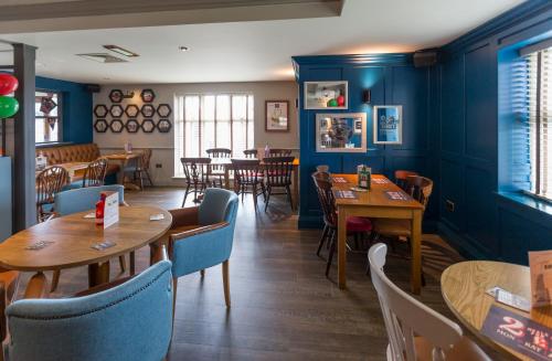 um restaurante com paredes azuis e mesas e cadeiras de madeira em Sessile Oak, Llanelli by Marston's Inns em Llanelli