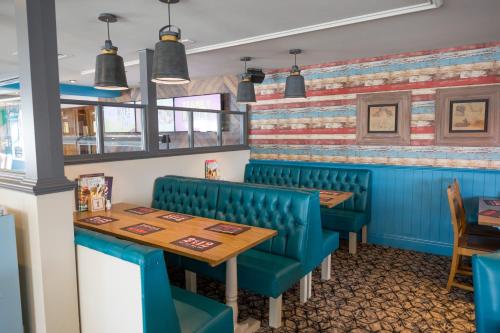 a dining room with blue chairs and a wooden table at Sessile Oak, Llanelli by Marston's Inns in Llanelli