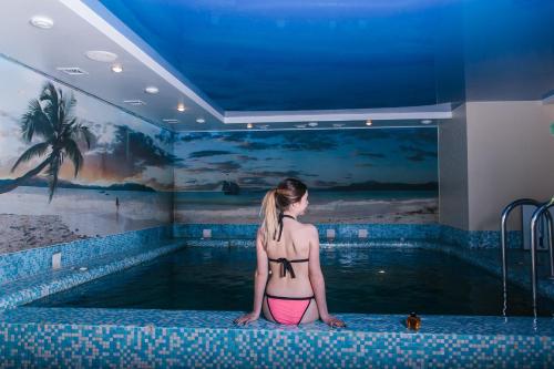 a woman standing in front of a swimming pool at Deluxe Hotel Kupava in Lviv