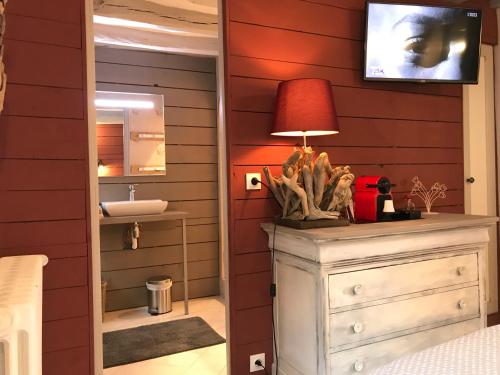 a bathroom with a sink and a lamp on a dresser at La tanière des ours in Chaumont-sur-Tharonne