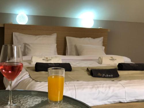 a table with a glass of wine and two beds at Mandula Apartman in Cegléd