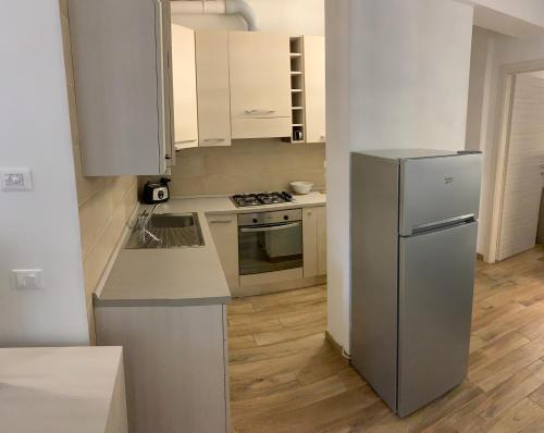 uma cozinha com armários brancos e um frigorífico de aço inoxidável em Ca du Sergio - Le Mura em Levanto