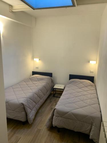 Duas camas num quarto com paredes brancas e pisos em madeira em Ca du Sergio - Le Mura em Levanto