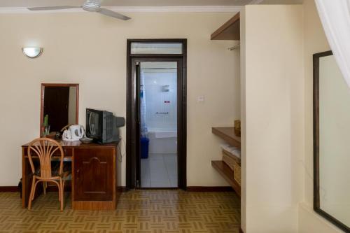 a room with a table and a television and a bathroom at Fahari Gardens Hotel in Nairobi