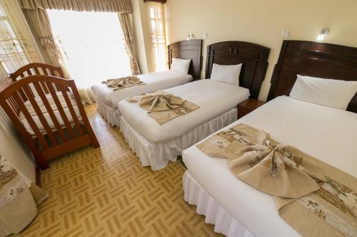 a hotel room with three beds and a window at Fahari Gardens Hotel in Nairobi