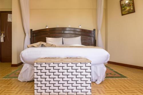 a bedroom with a large bed with a wooden headboard at Fahari Gardens Hotel in Nairobi