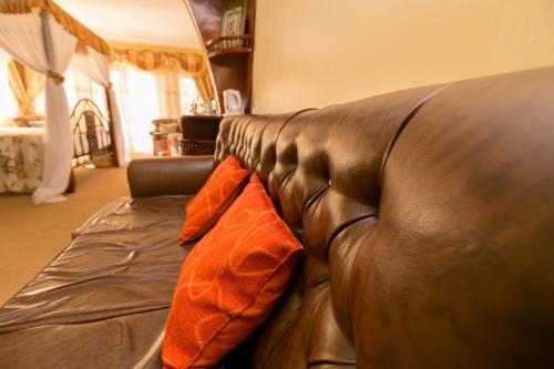 a brown leather couch with an orange blanket on it at Fahari Gardens Hotel in Nairobi