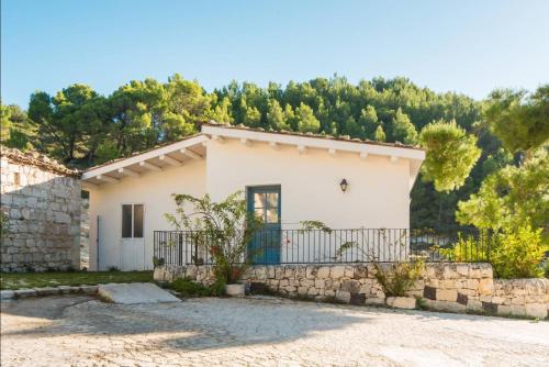 a small white house with a stone wall at Locanda Angelica in Giarratana
