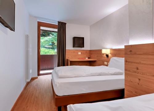 a hotel room with two beds and a window at Luna Wellness Hotel in Folgarida
