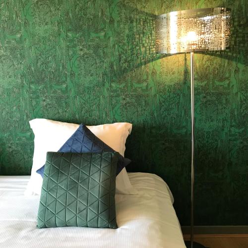 a bedroom with a bed with a green wall at Hôtel Restaurant Gastronomique La Huchette in Mâcon