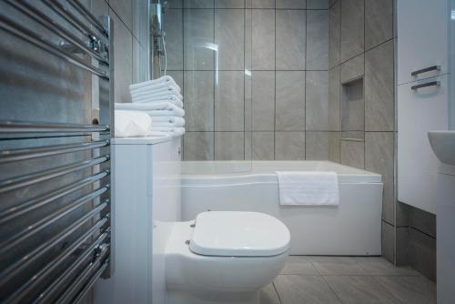a bathroom with a white toilet and a bath tub at Gordon Moon Suites Bolton Centre Apartments in Bolton