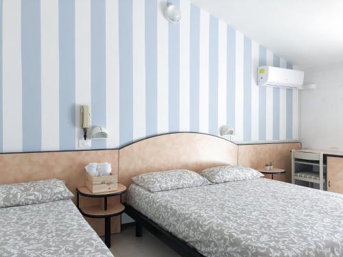 a bedroom with two beds and a striped wall at Alba B&B in Cattolica