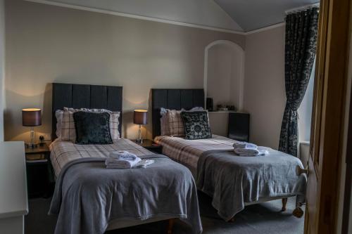 a bedroom with two beds and two lamps at Tregortha Guest House in Tighnabruaich