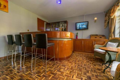 a bar with chairs and a tv in a room at Fahari Gardens Hotel in Nairobi