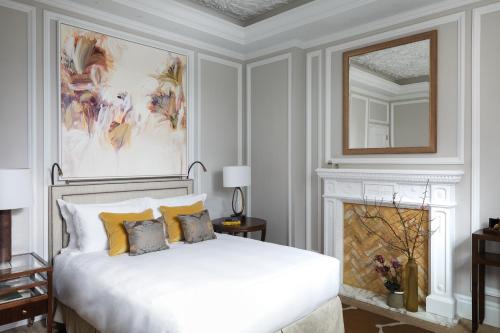 a bedroom with a white bed and a fireplace at The Cadogan, A Belmond Hotel, London in London