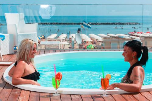 貝拉里亞－伊賈馬里納的住宿－Hotel Nettuno，两个女人坐在游泳池里喝饮料