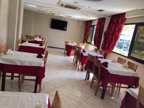a restaurant with tables and chairs and a flat screen tv at Hotel Amine in Sfax