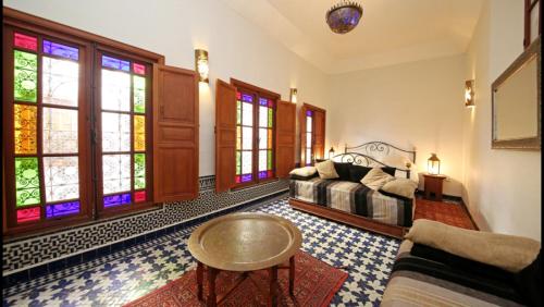 a living room with a bed and stained glass windows at Dar Abdesalam in Fès